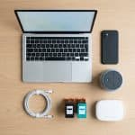 Flat-lay of everyday home tech: laptop, phone, router, ink cartridges, and speaker