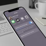 Image of an iPhone with cloud icons symbolizing storage optimization on a wooden surface.